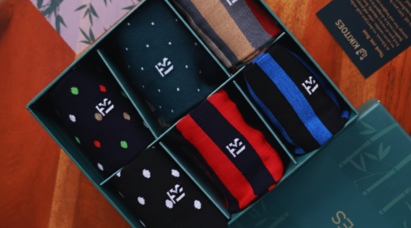 Premium corporate gift bamboo socks for men presented in a luxury green box with assorted striped and polka dot designs.
