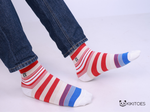 Man wearing red and white striped bamboo ankle socks with blue toe and heel accents paired with denim jeans.