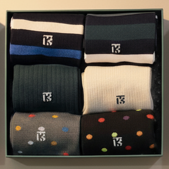 Three boxes of socks with a green box labeled 'Feetures' on a beige surface.