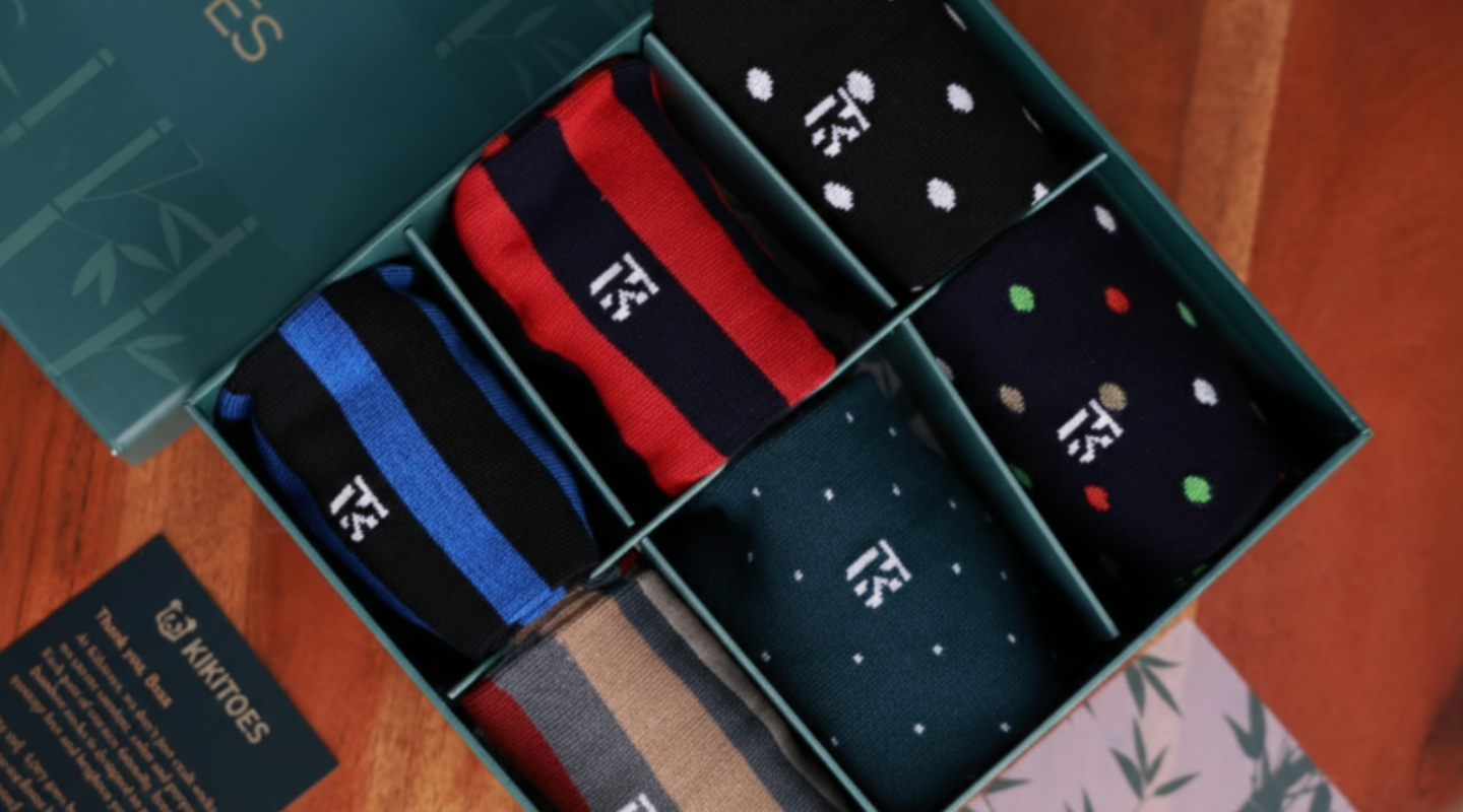Premium corporate gift bamboo socks for men presented in a luxury green box with assorted striped and polka dot designs.